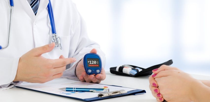 A male doctor showing a glucose monitor to a female patient.