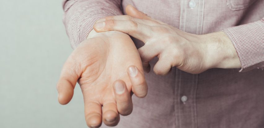 A man checking his pulse by placing two fingers on his wrist. 
