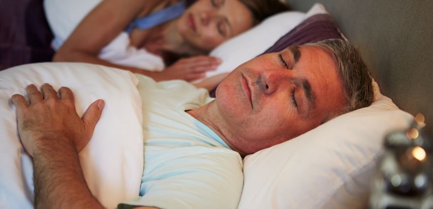 A married couple sleeping in a bed.