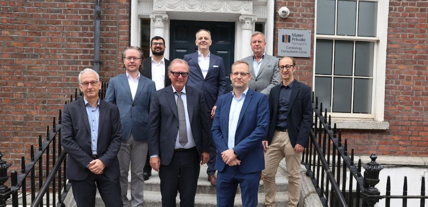 A group of men in suits posing in front of a red brick building.