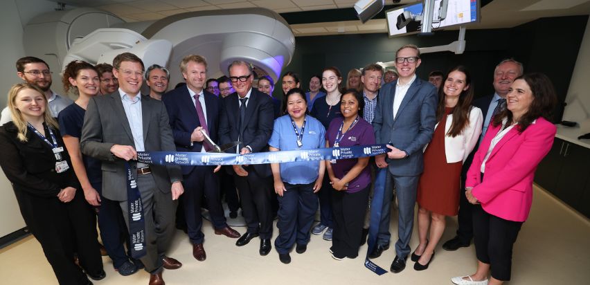Linac Dublin A group of people standing in front of a radiotherapy machine, cutting a ribbon