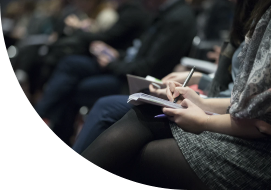 A group of people at an event, taking down notes in their notebooks.