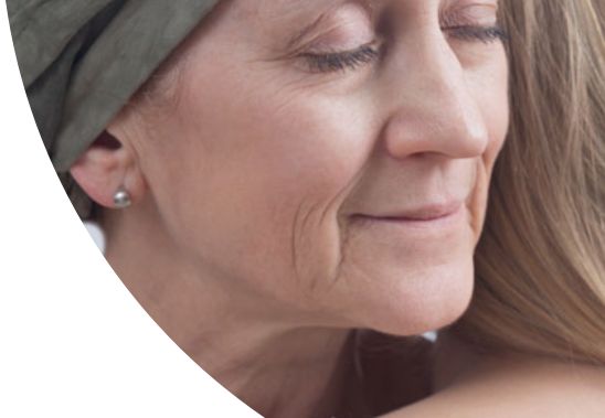 A female cancer patient hugging another female.