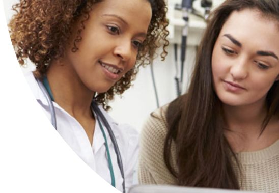 A female doctor and female patient looking at a tablet together.
